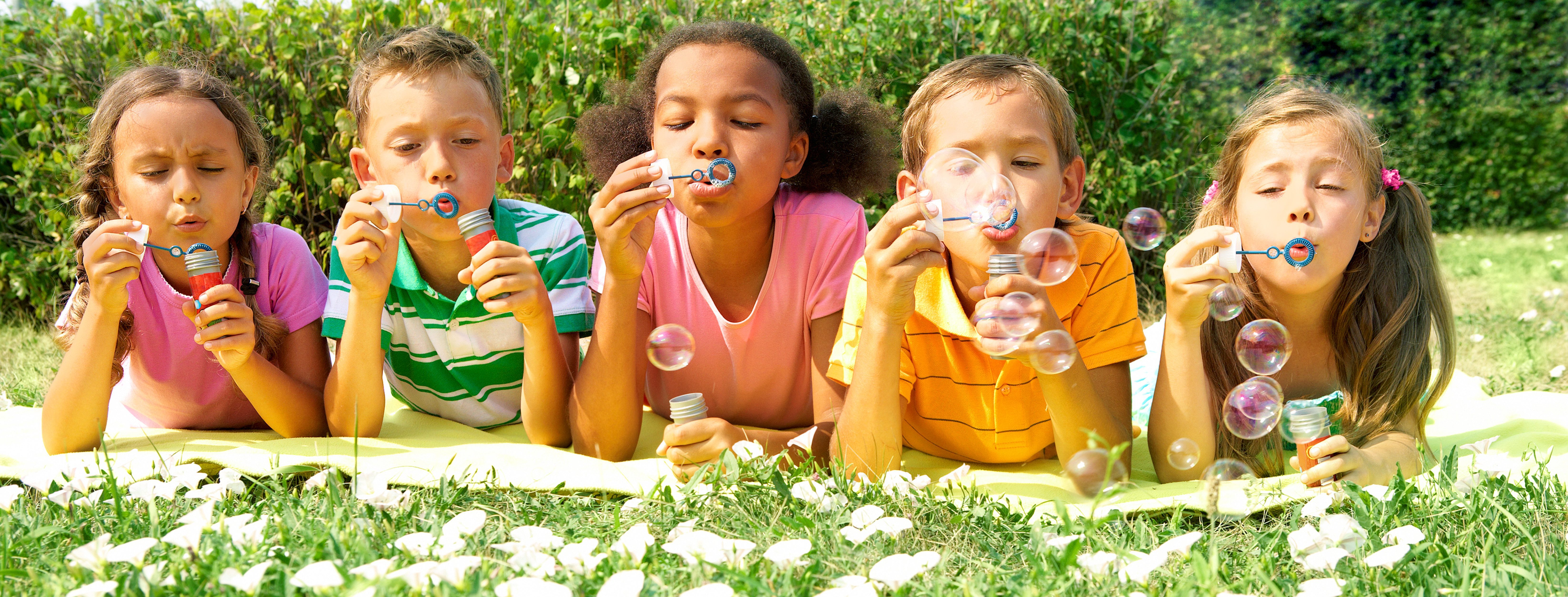 Kids blowing bubbles in grass